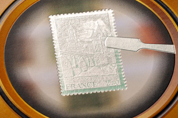 Briefmarkenähnliches, silbern metallisches Prägemotiv unter einer Lupe mit feiner Oberflächenstruktur, Haus sowie den Schriftzügen „RF“ und „FRANCE“